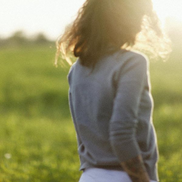 Person meditating in a calm, natural setting with soft morning light.